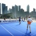 Janko Tipsarevic of Serbia returns a shot as doubles partner Nico Hulkenberg of the Force India Formula 1 racing team watches on in a match on a temporary court placed on Singapore's Marina Parade promenade during the ATP World Tour's promotion of its Asian swing; Getty Images for ATP