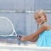 Girl (6-7) playing tennis, smiling