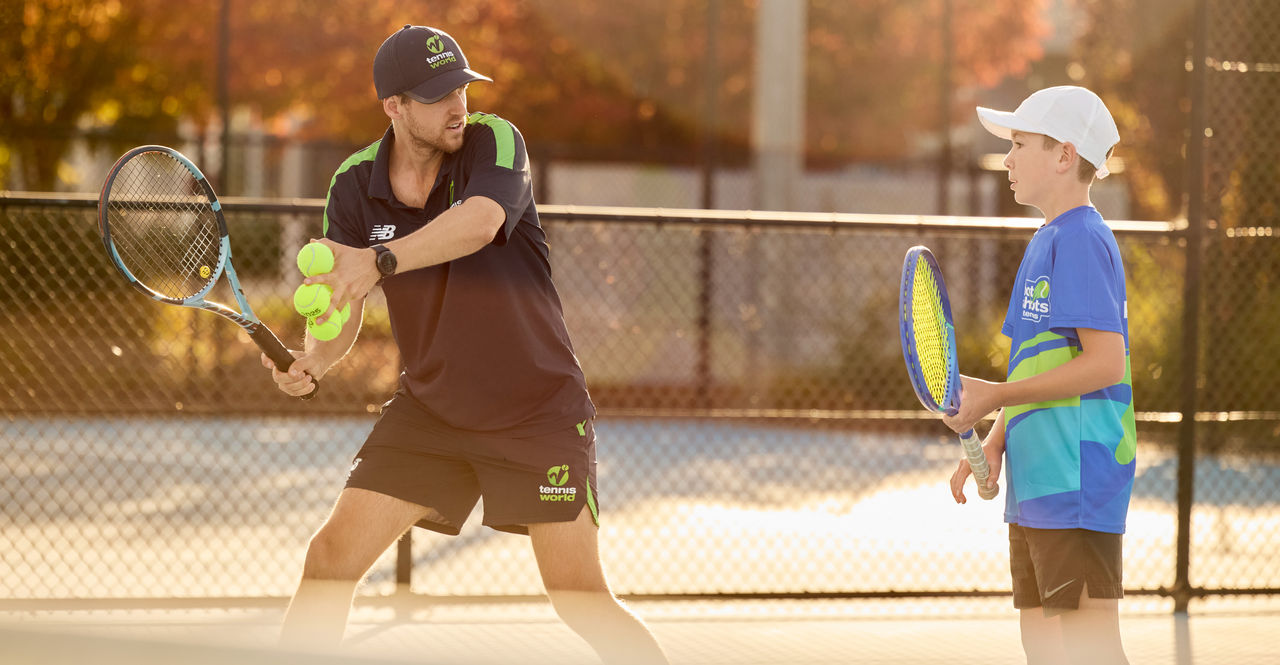 Tennis coach shows technique to primary school student